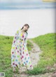 A woman in a white dress standing on a dirt road.