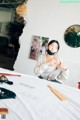 A woman sitting on top of a bed next to a mirror.