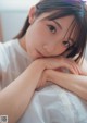 A woman laying on top of a bed with her hand on her chin.